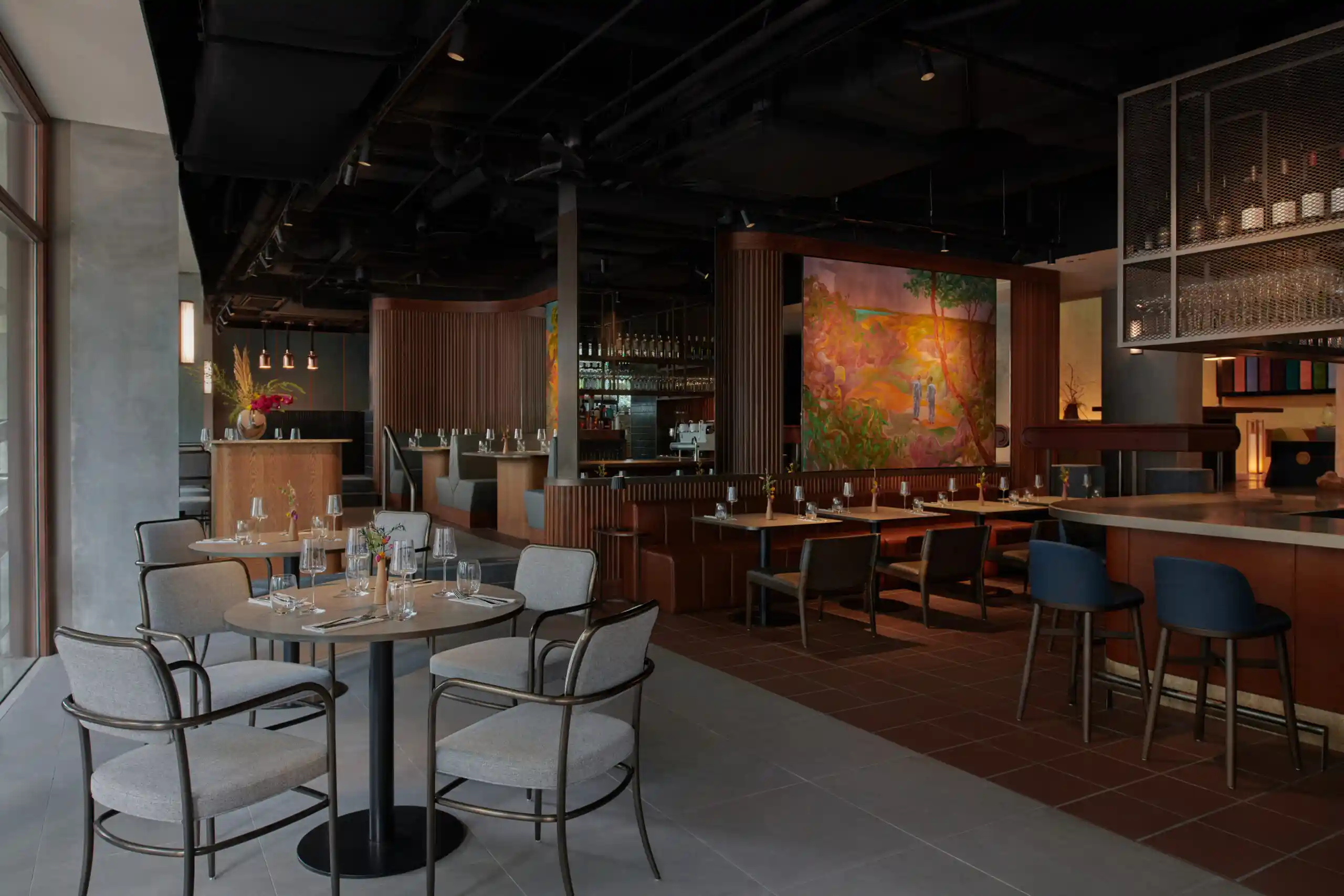 Modern restaurant dining area with wooden accents, booth seating and warm ambient lighting.