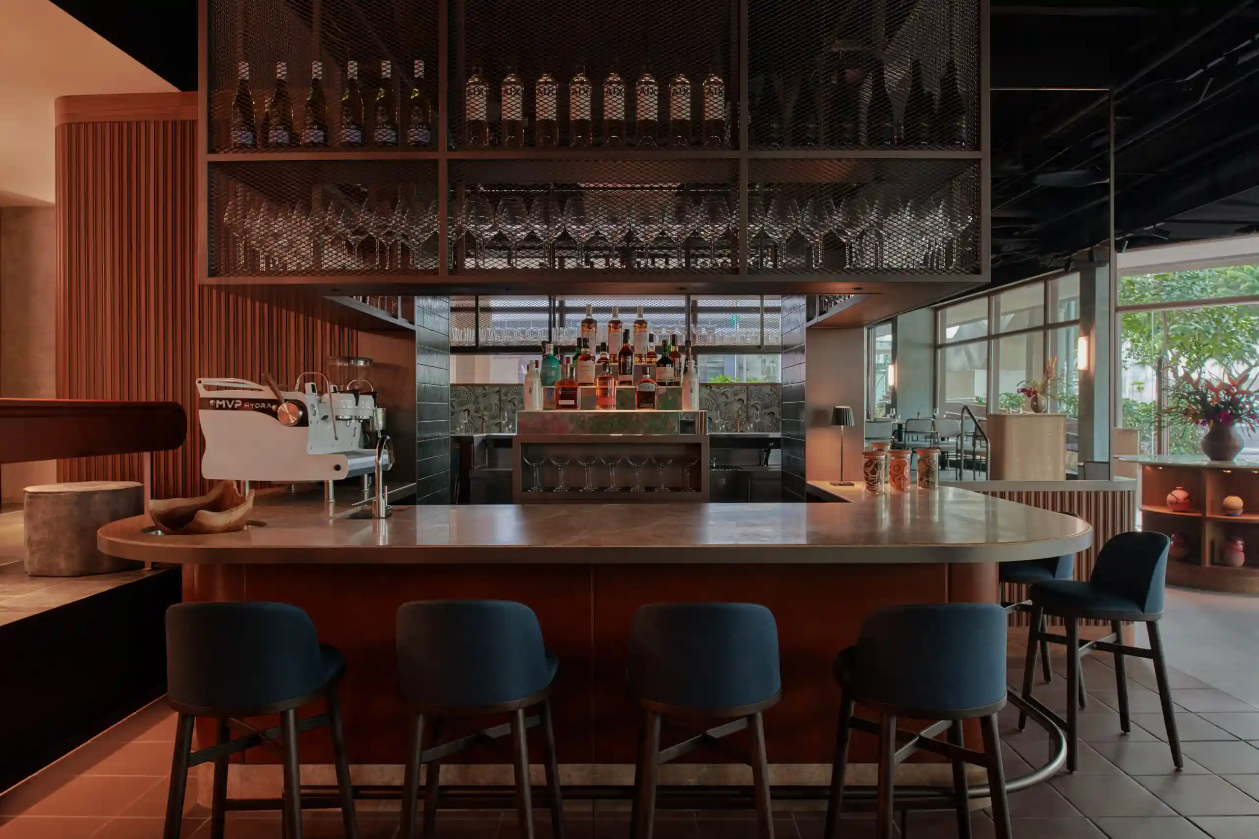 Stylish restaurant bar with seating, warm lighting and a selection of spirits on display.