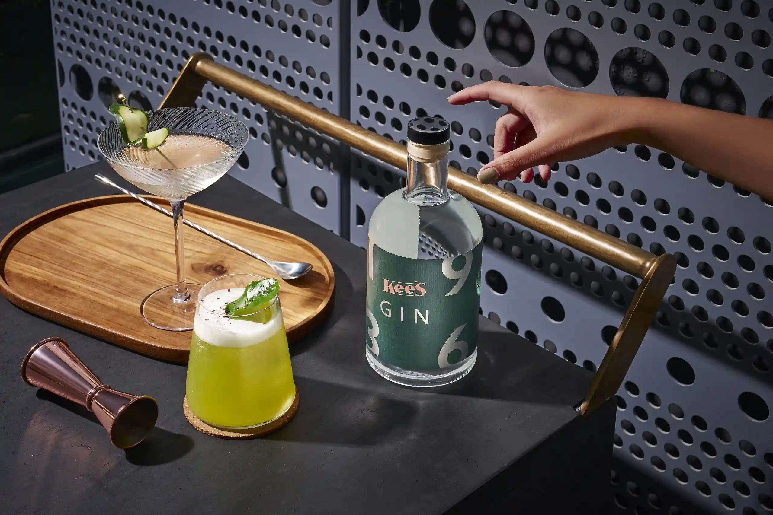 Signature cocktails with Kee’s gin bottle and bar tools on a modern tray setup.